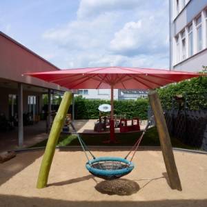 Sonnenschirm mit rotem Dach auf dem Spielplatz der Kita Zwergtaucher